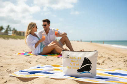 A nautical-themed "Rule #1 Don't Fall Off The Boat" pouch displayed on a sunny beach.