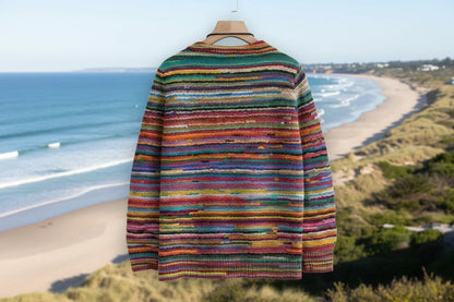 Colorful striped sweater on a hanger with a beach and ocean in the background