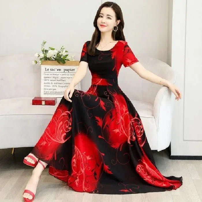 Elegant woman in red-and-black floral dress standing in grand ballroom — showcasing sophisticated drape and refined neckline.