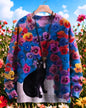 Black cat sitting in a field of colorful flowers on a bright blue 3D sweater