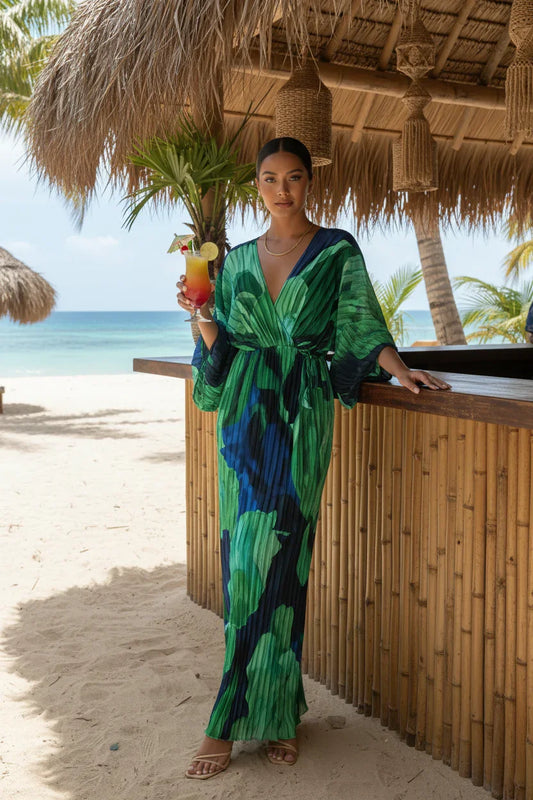 Front view of woman in green and blue abstract print v-neck maxi dress at a beach bar.