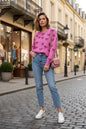 Bold magenta pink pullover with black bow designs, styled with blue jeans for casual fall travel.