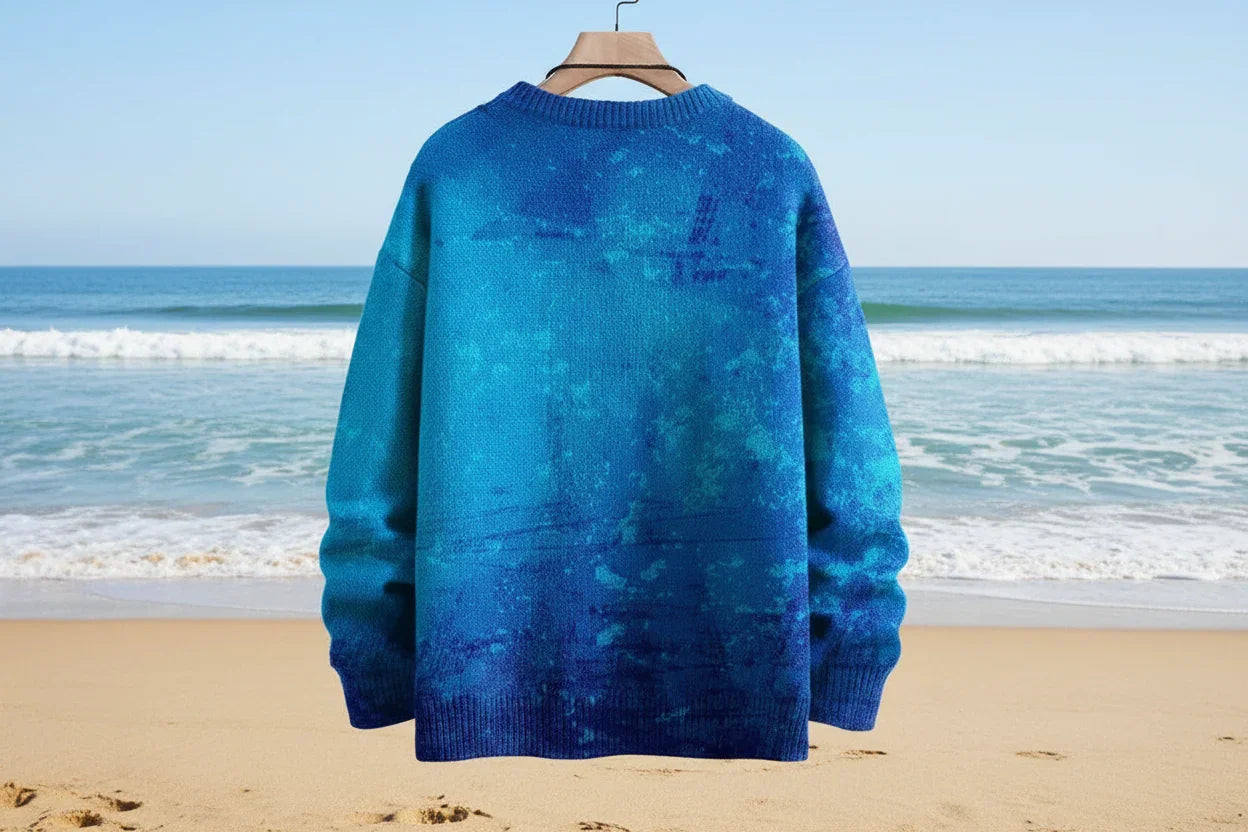 Blue sweater on a hanger against a beach backdrop