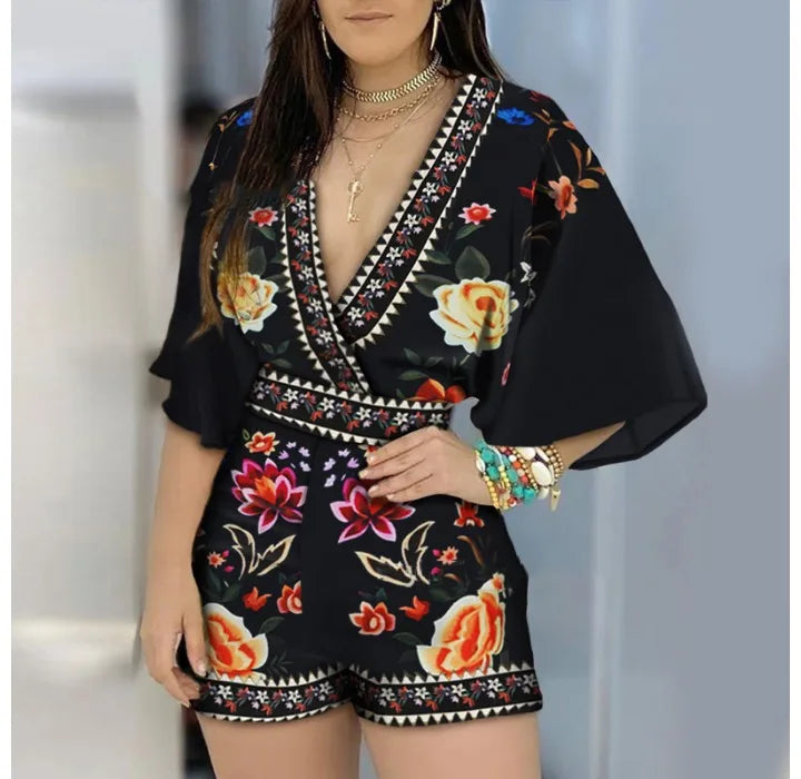 Woman in a black and floral printed romper with fitted waist and flowy sleeves
