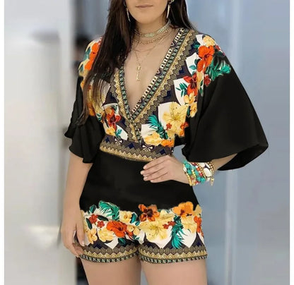 Woman wearing a black floral romper with yellow and red roses, posing outdoors