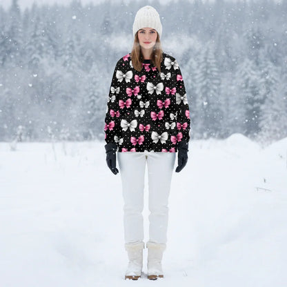 Black winter-ready sweatshirt with clusters of pink, white, and red bows, worn in a snowy forest landscape.