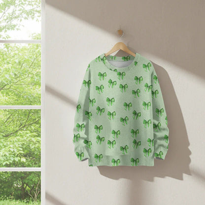 Mint green sweatshirt with emerald bow prints hanging against a white wall.