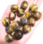 Hand holding polished tiger's eye tumbled stones for courage and confidence - natural feng shui crystal healing