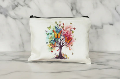 White pouch with a colorful tree and butterflies design on a wooden surface.