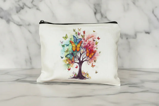 White pouch with a colorful tree and butterflies design on a wooden surface.