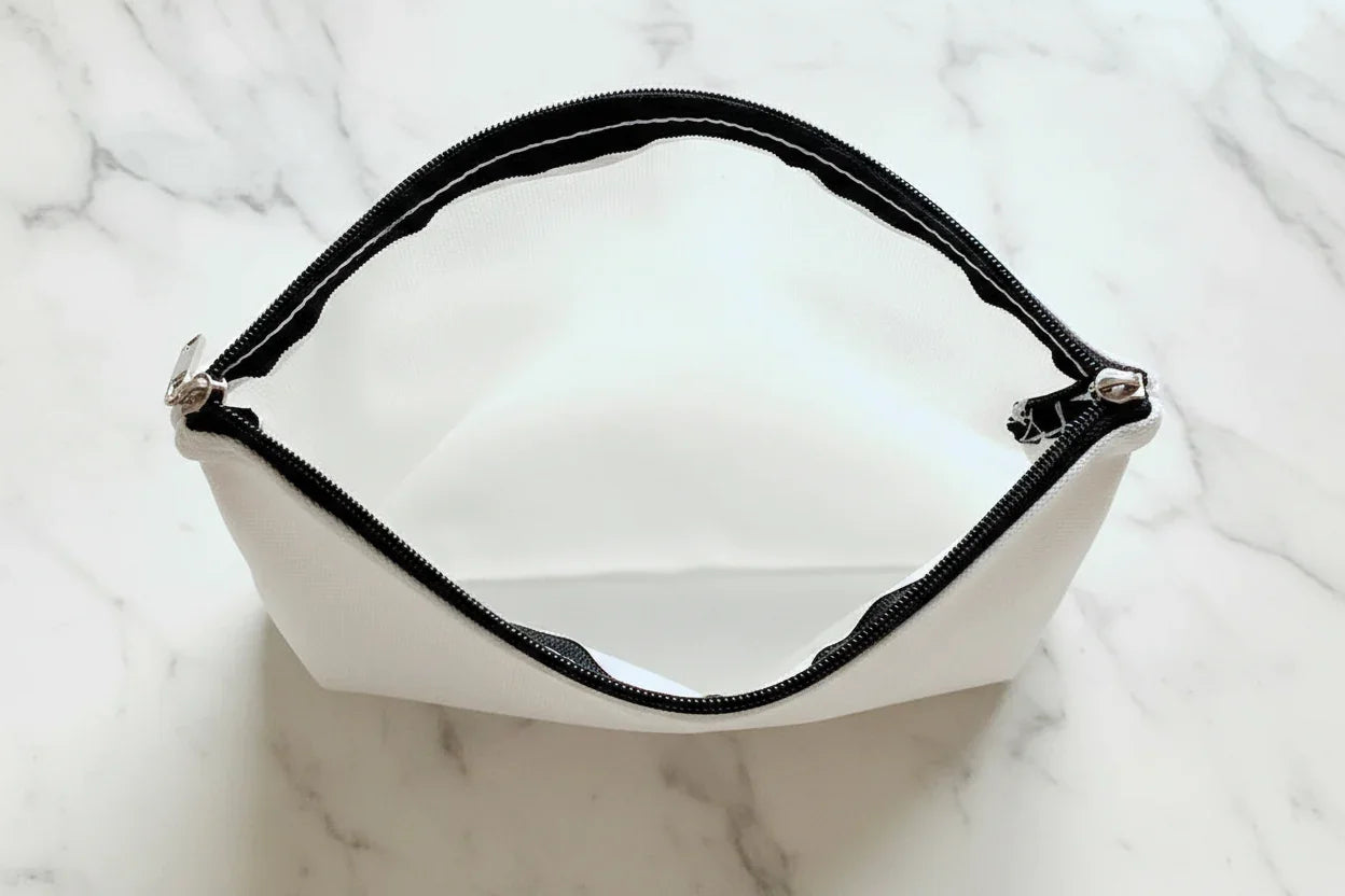 White pouch with black zipper on a marble surface