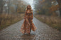 Woman in a floral dress walking on a cobble path in a natural setting