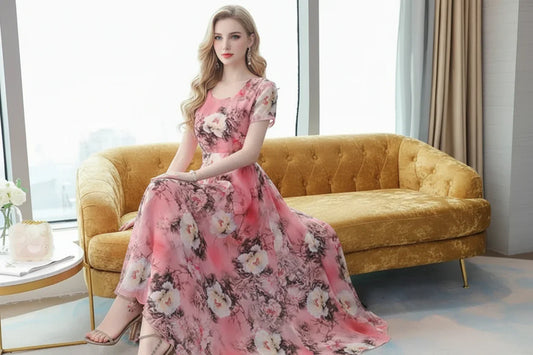 Woman in a floral pink dress sitting on a modern couch in a bright room.