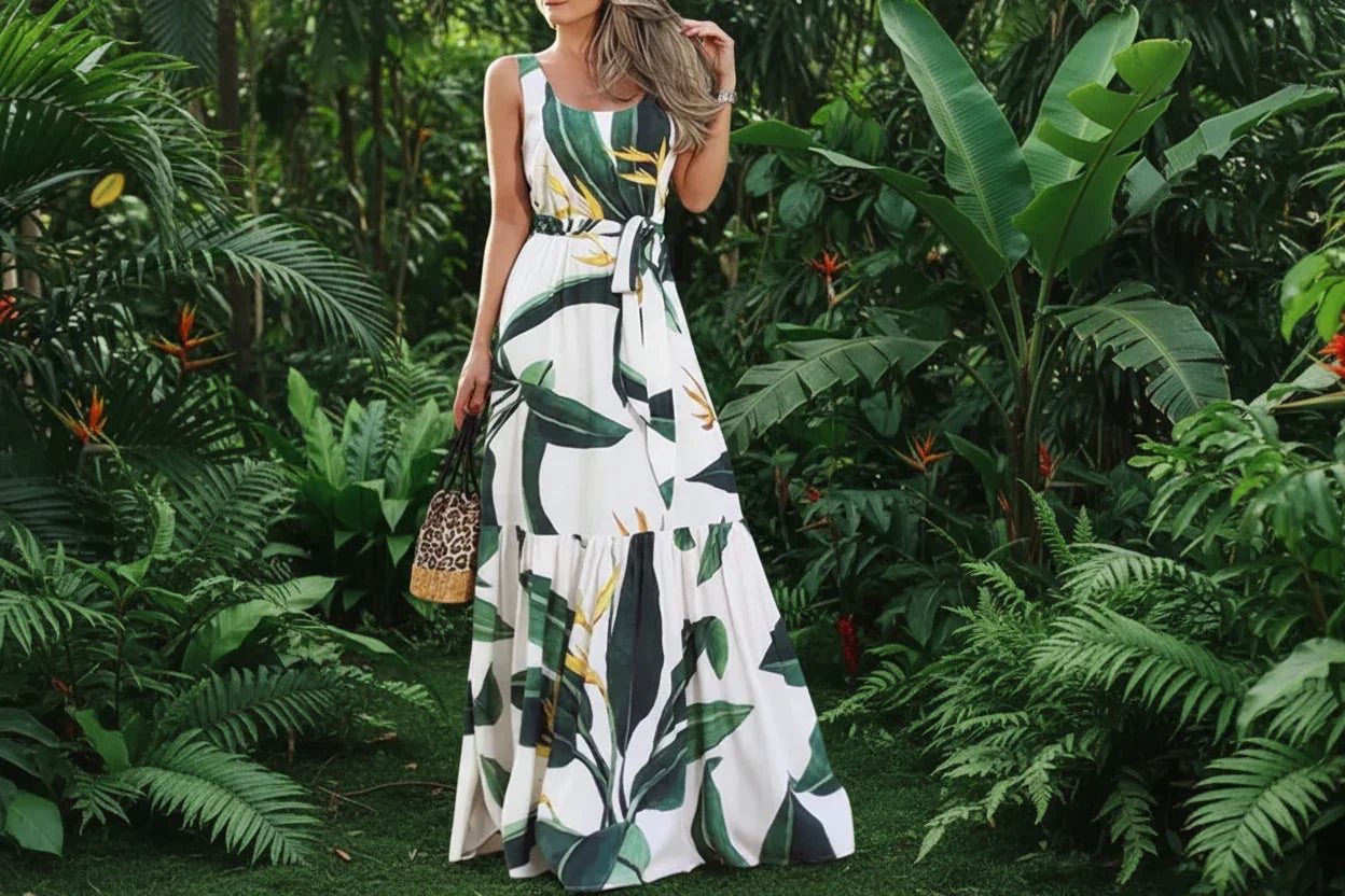 Woman wearing a long, sleeveless dress with a tropical leaf pattern in an outdoor setting.