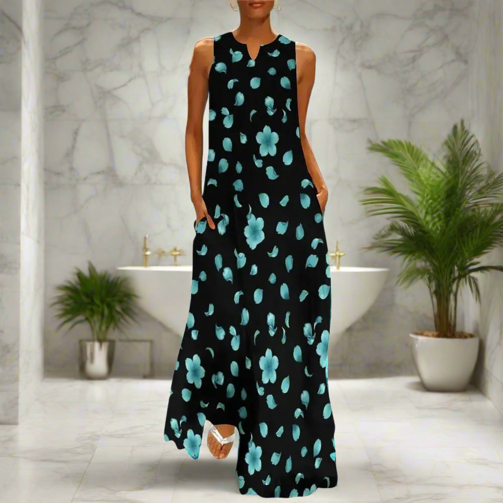 Chic sleeveless black maxi dress with scattered aqua blue floral patterns, modeled in a stylish modern bathroom