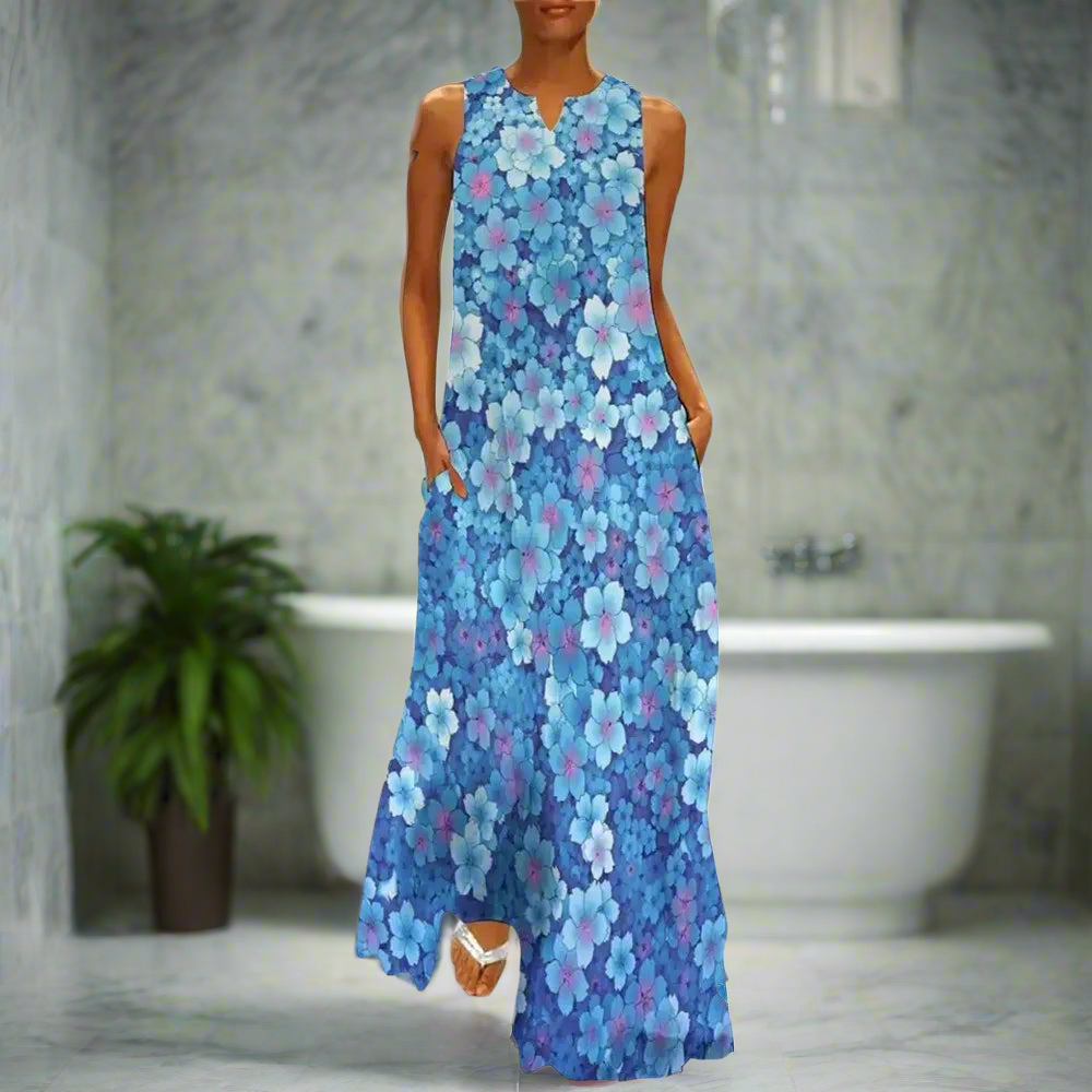 Vibrant blue floral sleeveless maxi dress with multicoloured flower pattern, modelled in a bathroom with marble decor
