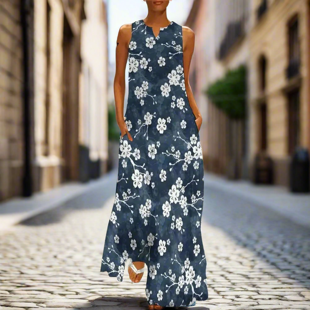 Sleeveless navy blue floral maxi dress with white blossoms, modelled on a cobblestone street