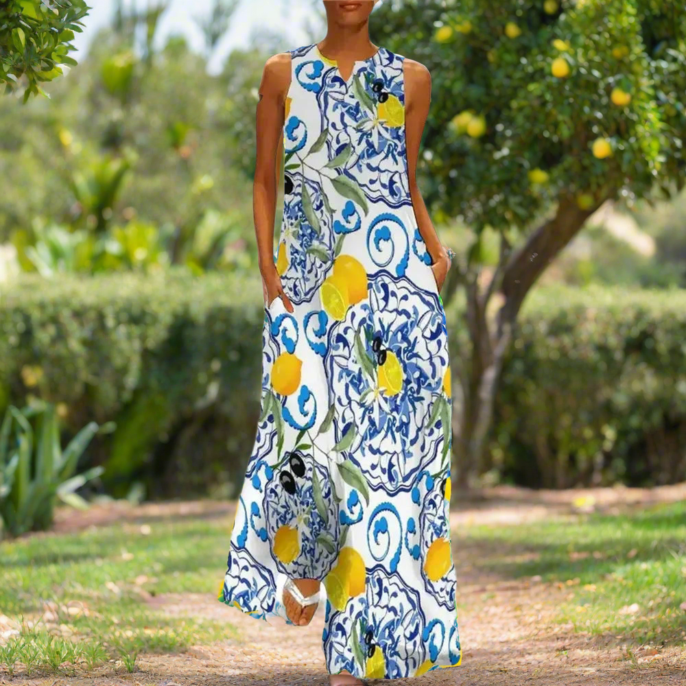 Bohemian sleeveless maxi dress with vibrant lemon and blue floral print, modeled in a sunny garden setting