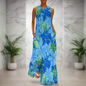 Blue floral-themed sleeveless maxi dress with light and dark flower clusters, worn in a modern bathroom setting.