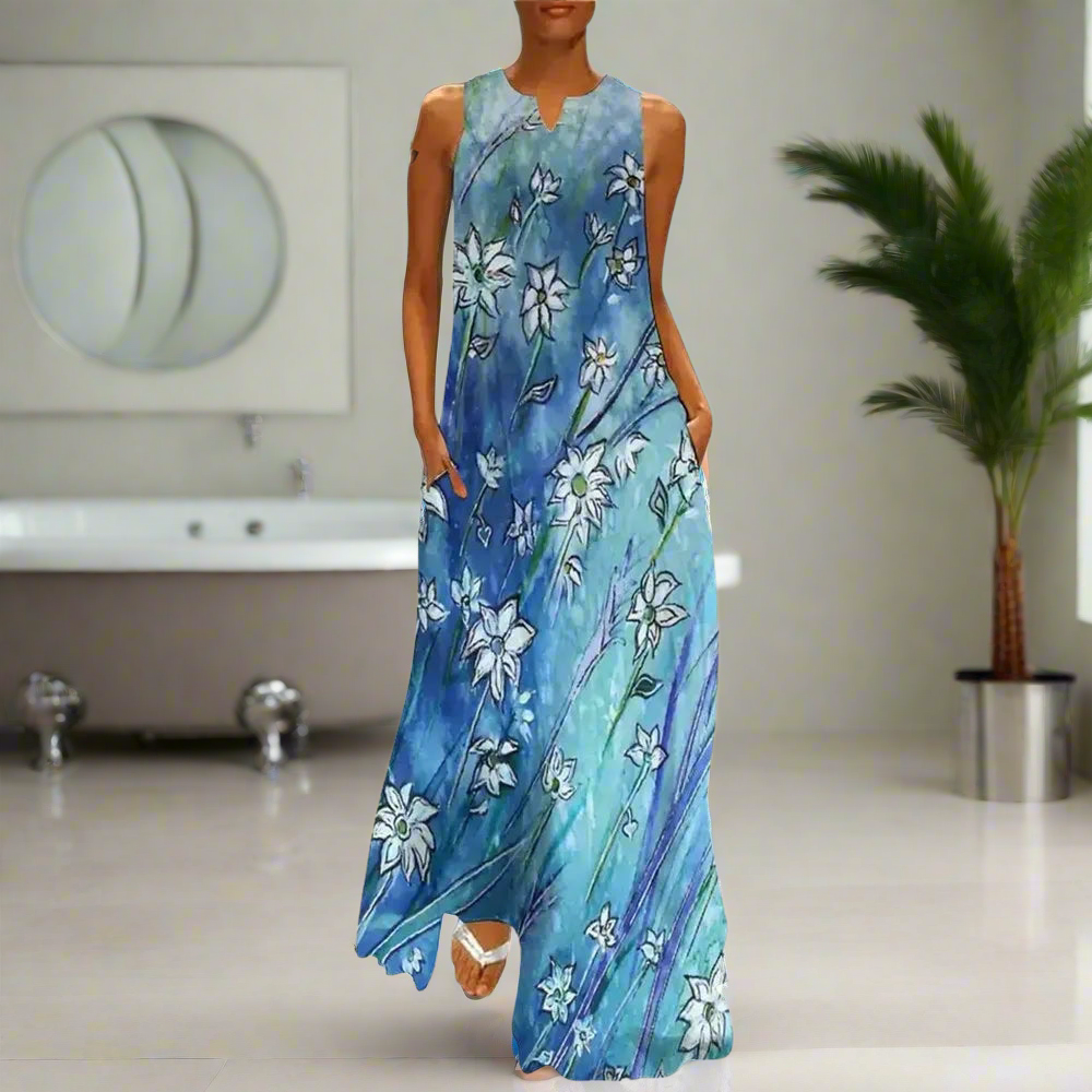 Sleeveless navy blue maxi dress with white floral print, worn by a woman walking down a cobblestone street