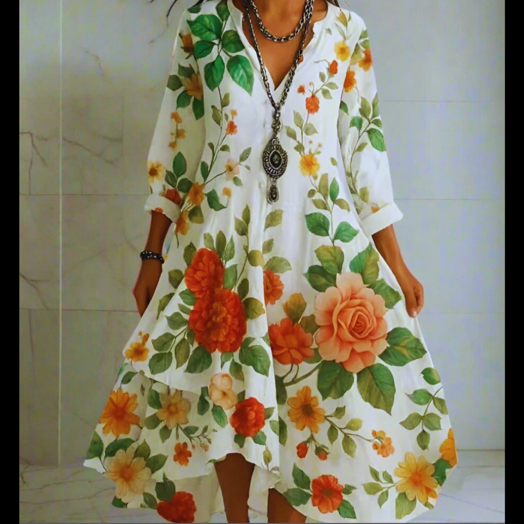 Close-up of a white dress with large orange rose prints, showcasing intricate floral details and loose sleeve design.