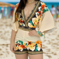 Woman wearing a cream-colored romper with multicoloured floral prints and geometric borders, standing on a beach
