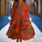 Long orange floral dress with half sleeves and asymmetrical hem, worn on a cobblestone path.