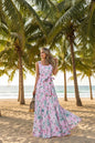 Woman wearing a pink floral dress standing outdoors with palm trees in the background